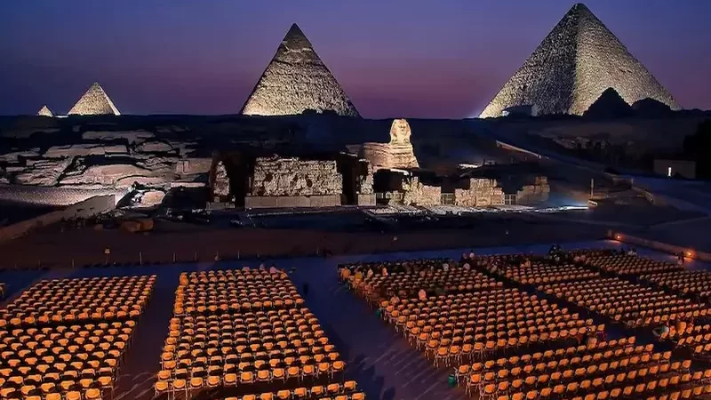 Night view of the Pyramids of Giza and the Sphinx illuminated in colorful lights during the sound and light show