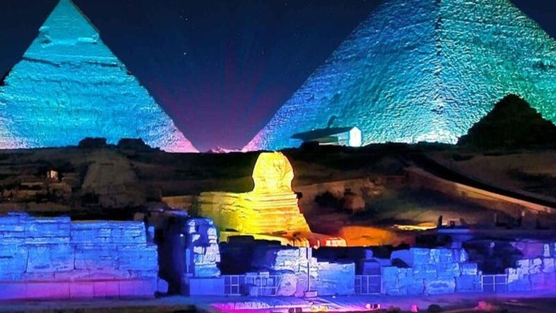 Night view of the Pyramids of Giza and the Sphinx illuminated in colorful lights during the sound and light show