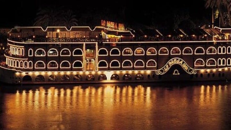 Night view of the illuminated Maxim Nile cruise restaurant reflecting on the Nile River in Cairo, Egypt