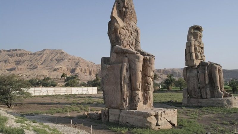 The towering Colossi of Memnon statues standing at the entrance of ancient Thebes in Luxor