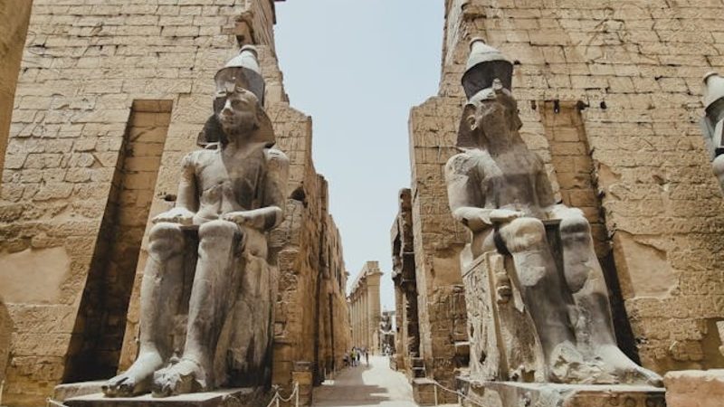 Seated statues of ancient pharaohs at the monumental entrance of Luxor Temple in Egypt.
