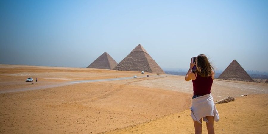 Young tourist taking a picture of the Giza Pyramids during her 7 Day Egypt Trip